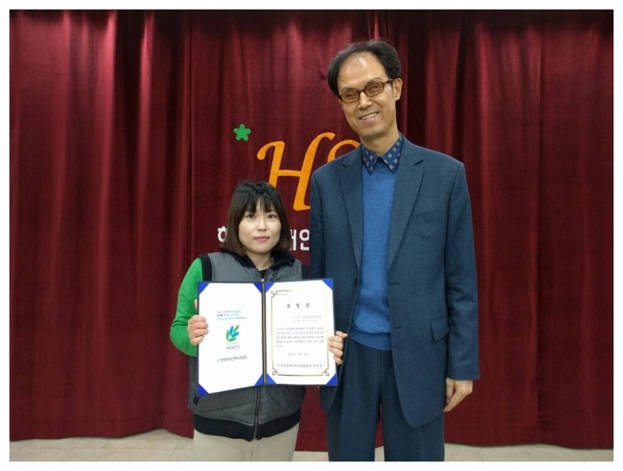 교육치료팀 이지언 선생님과 김호식 관장님이 표창장을 들고 기념사진을 찍고 있는 모습