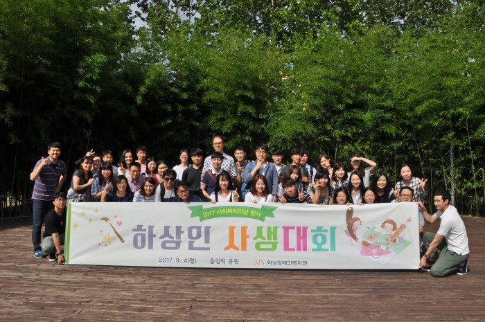 하상인사생대회 라는 현수막을 들고 복지관 직원들이 단체사진을 찍고 있다.