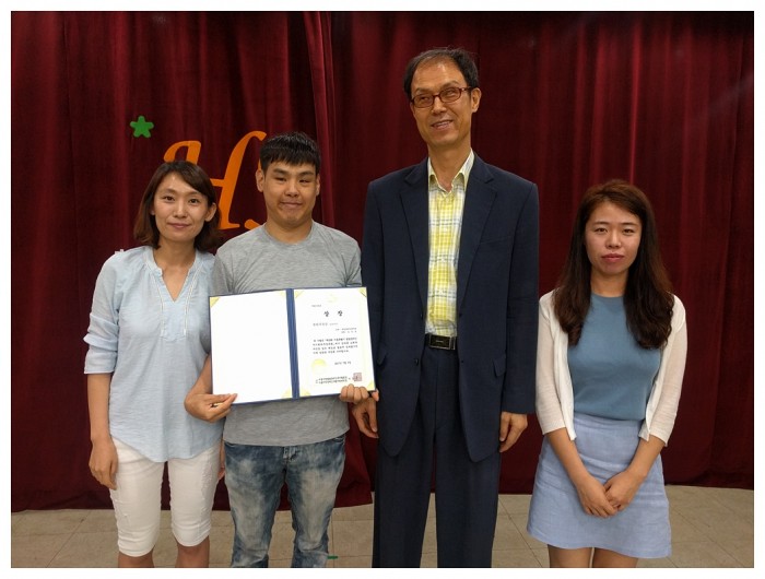 복지관 강당에서 권리주장상을 수상한 김진성님과 직업재활팀 직원, 김호식 관장님이 수상 후 기념사진을 찍고 있는 모습