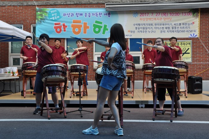 무대에 올라 채를 들고 율동과 북을 치면서 난타공연을 하고 있는 주간보호센터 이용자 
