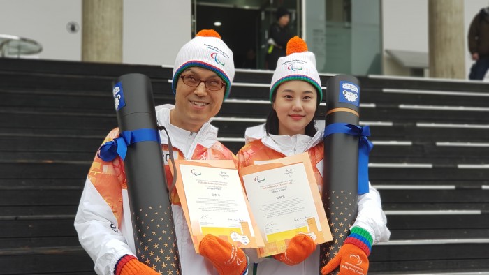 김호식관장님이 성화와 주자증서를 들고 동행주자와 기념사진을 찍는 모습