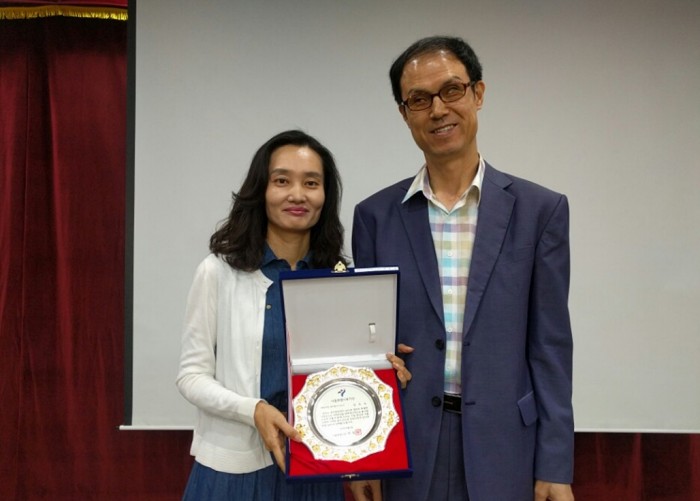 복지관 강당에서 남은숙 부장이 상패를 들고 김호식 관장과 기념사진을 찍고 있는 모습