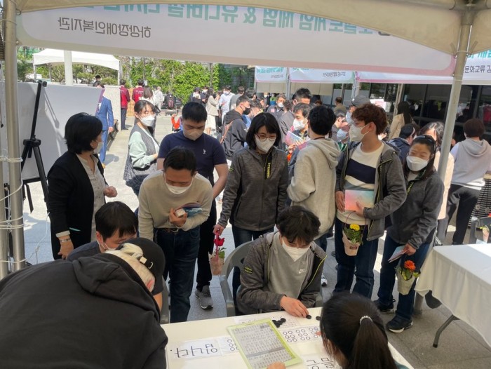 지역주민들이 체험부스에서 본인의 이름을 점자로 쓰고 있는 사진