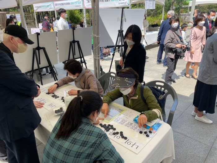 지역주민들이 체험부스에서 본인의 이름을 점자로 쓰고 있는 사진